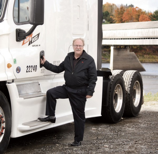 John Doucet, president and CEO of The Day & Ross Transportation Group, gets hands-on with a truck in Hartland, New Brunswick, with the world’s longest covered bridge in the background.