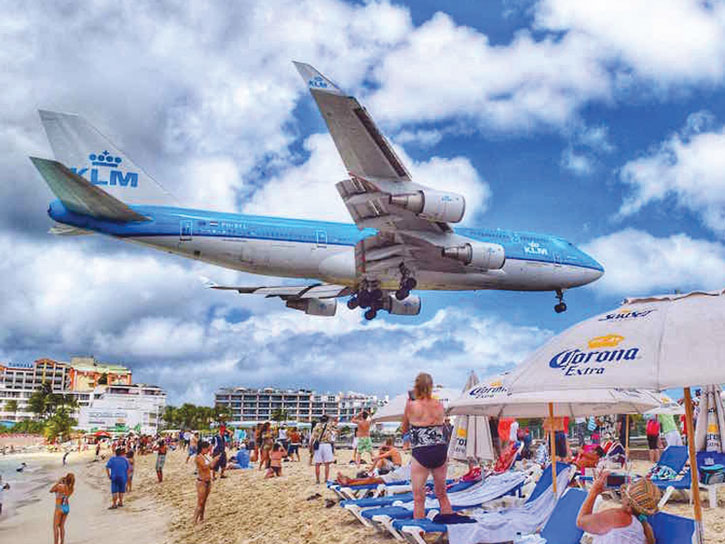 On its descent to the airport, a KLM Boeing aircraft flies over Maho Beach on Saint Martin in the Caribbean.
