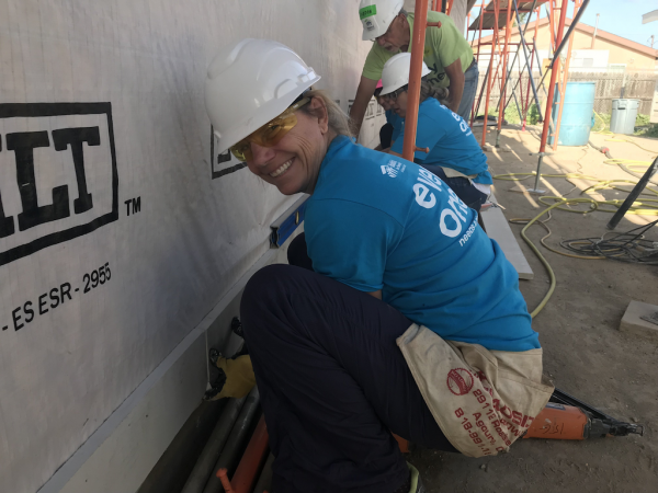  CEO and Port Director Kristin Decas helps to put up siding on a residence.