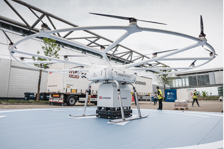 Experts from Volocopter and DB Schenker conduct the first test run of ground operations for the VoloDrone in logistics at Messe Stuttgart. An autonomous mobile Robot by Gideon Brothers transports the payload box under the heavy lift drone Picture Credit: Volocopter/DBSchenker