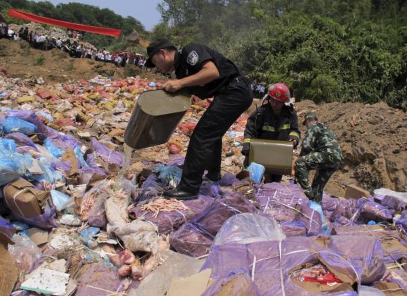 Police officers pour gasoline on confiscated smuggled meat before setting it on fire during a massive destruction campaign in Hekou county, Yunnan province, China, July 8, 2015. Reuters/China Daily 