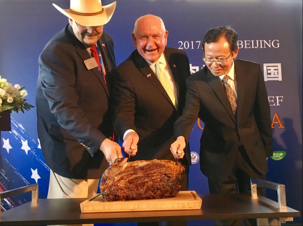 U.S. Secretary of Agriculture Sonny Perdue (center) ceremonially cuts into a Nebraska prime rib in Beijing, marking the return of U.S. beef to the Chinese market. Perdue is joined by Craig Uden (left), president of the National Cattlemen's Beef Association, and Luan Richeng (right), of state-owned Chinese importer COFCO. 