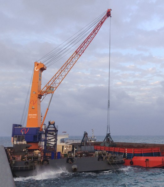 One of Winning Logistics’ four floating cranes transshipping bauxite from barges to oceangoing vessels off the coast of Guinea.