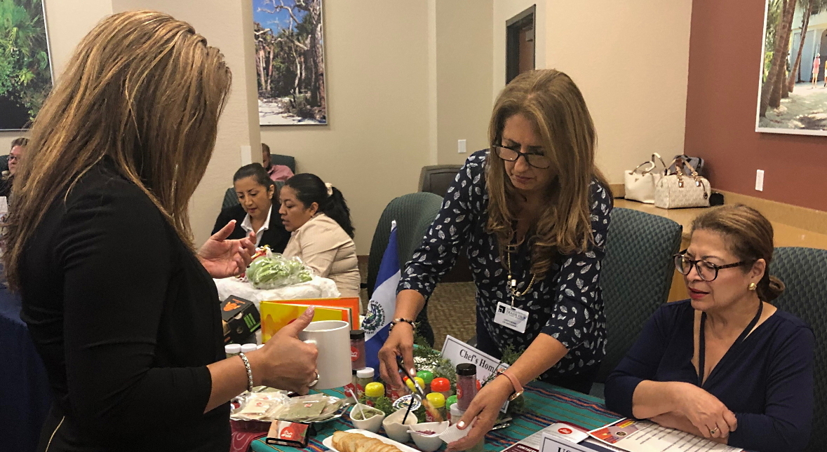 A visitor to the International Trade Hub at Port Manatee’s Aug. 27 expo-style event in Fort Myers makes a business connection while sampling spices imported from El Salvador.