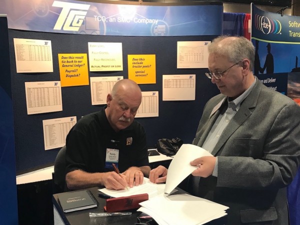 Randy Vernon of Big G Express signs the contract at the TCA annual convention while Jack Jones of TCG looks on